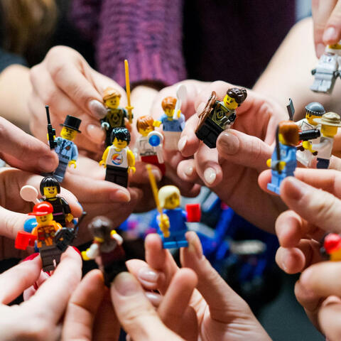 Hands holding LEGO® minifigures together